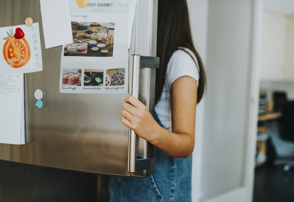 Girl picking something to eat out of the fridge