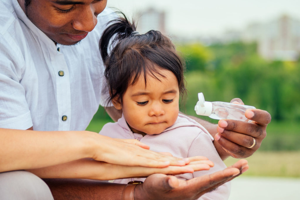 happy family applying hand-sanitizer anti-bacterial gel to daughter hands